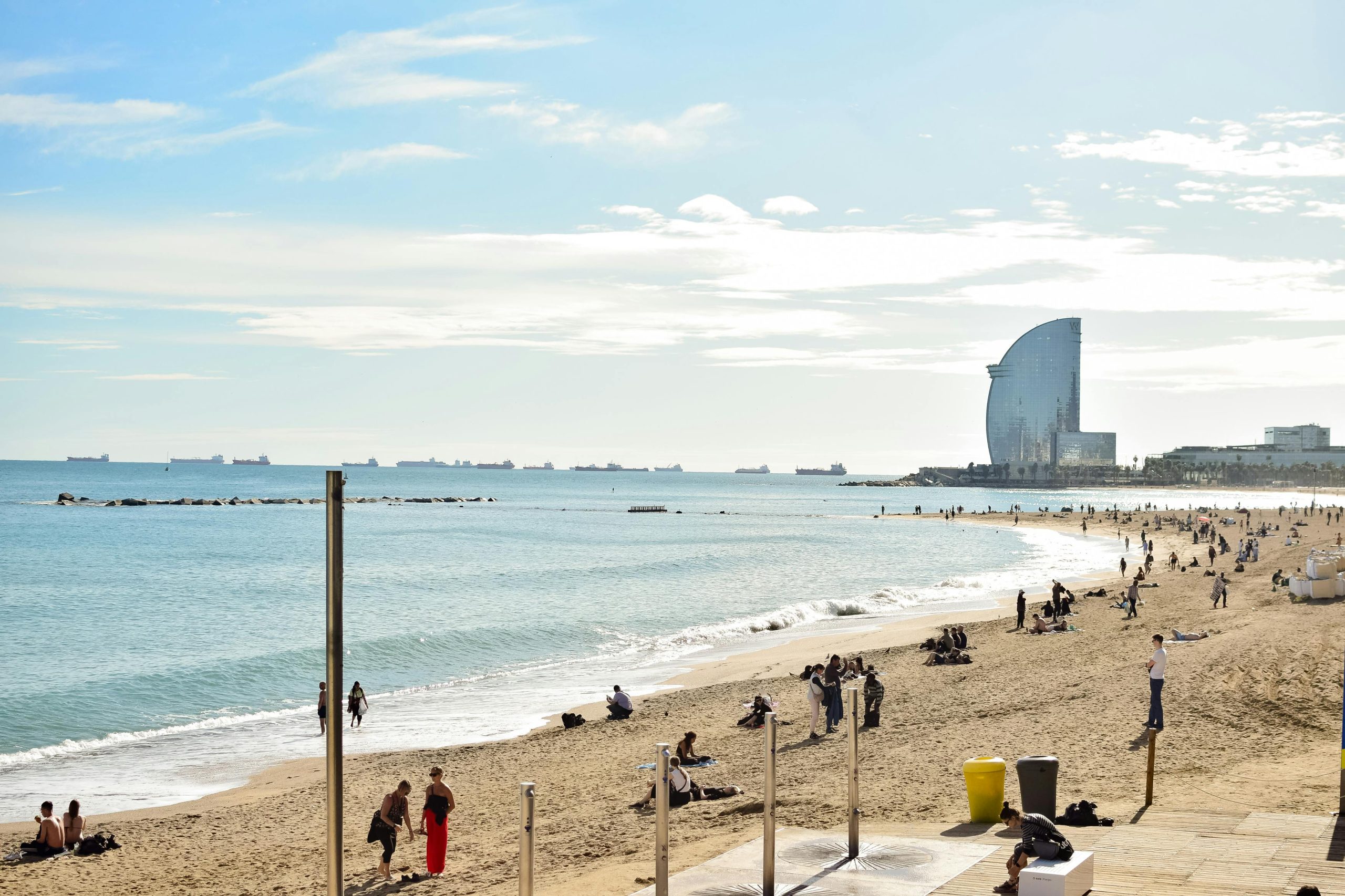 Capture of Barceloneta Beach on a sunny day with people enjoying the coastline in Barcelona.